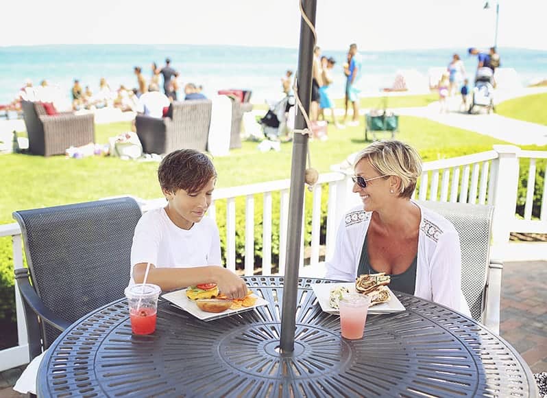 Mom and son enjoy food and drinks at outdoor Cabana Bar in summer, Inn at Bay Harbor