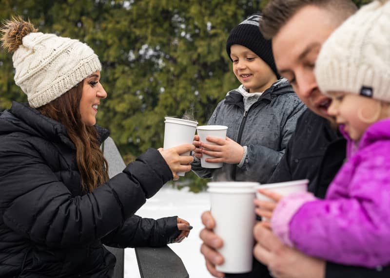 Family toasting with hot chocolates outside in winter