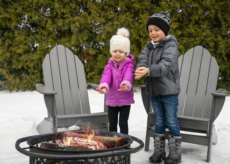 Kids warming hands at winter bonfire in snow