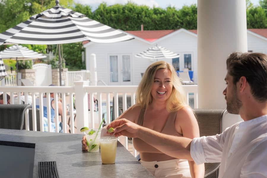 Couple enjoys drinks at poolside Cabana Bar in summer, Inn at Bay Harbor