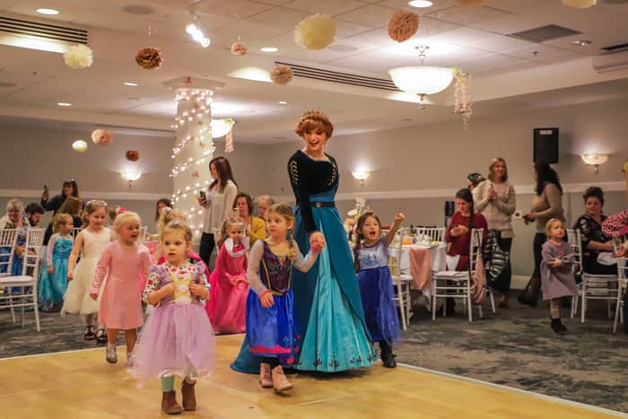 Anna leads young guests around the ballroom during the 'Princess Parade' activity