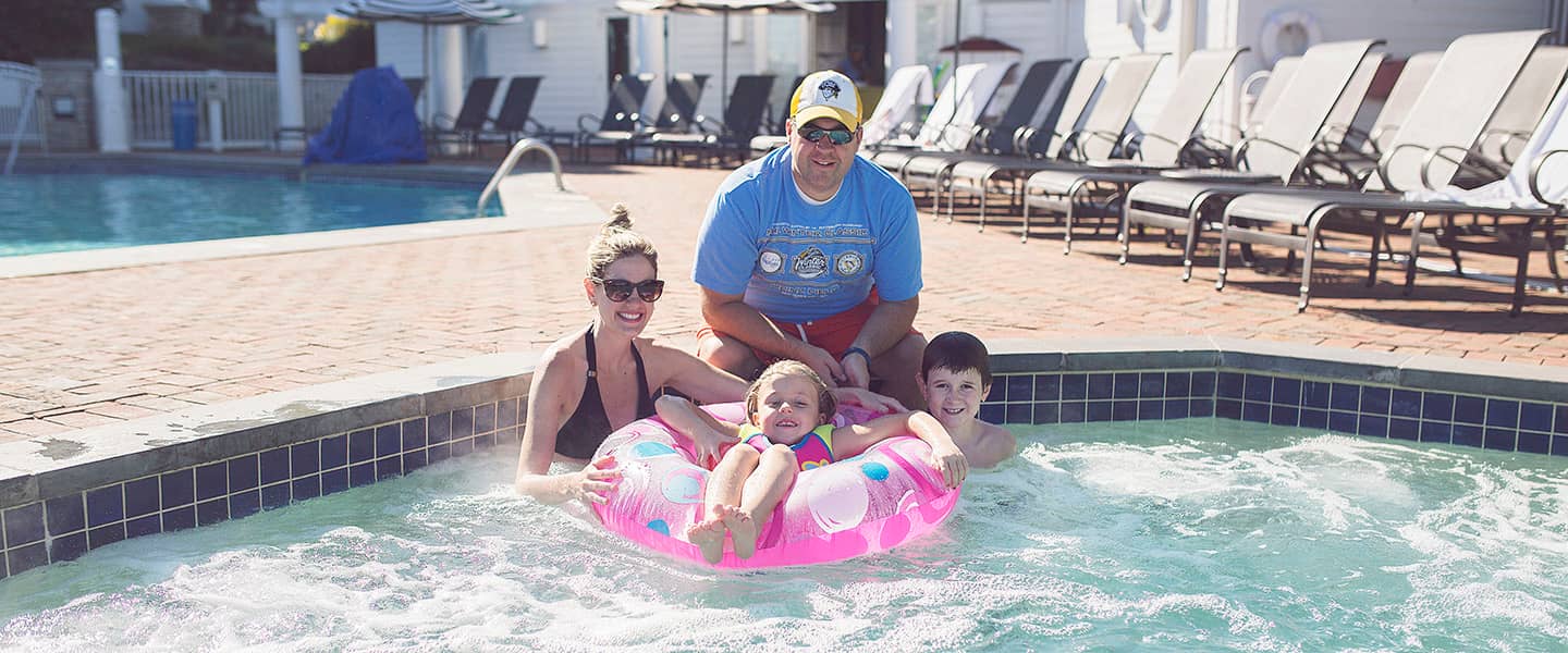 Family poses with pool toys in hot tub at Inn at Bay Harbor