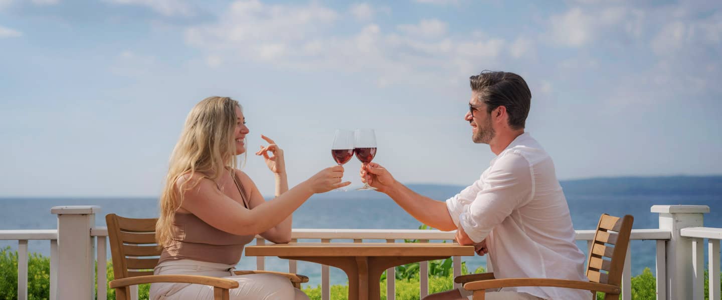 Couple toasts with red wine along water - Up North Uncorked Series, Inn at Bay Harbor
