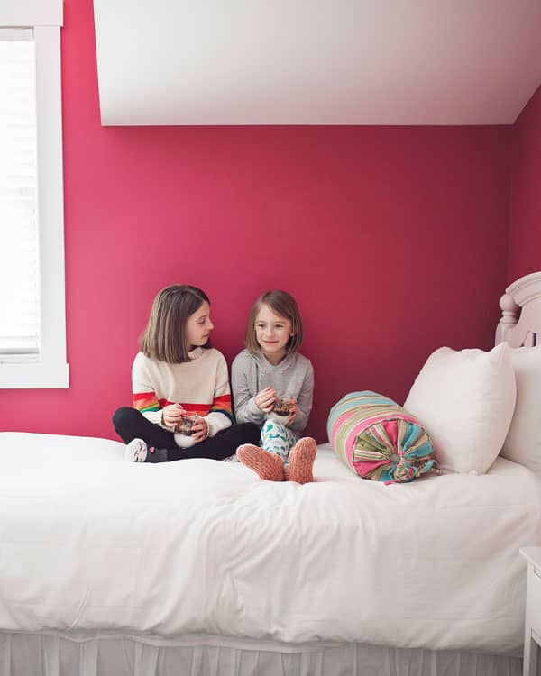 sisters eating on bed in pink room