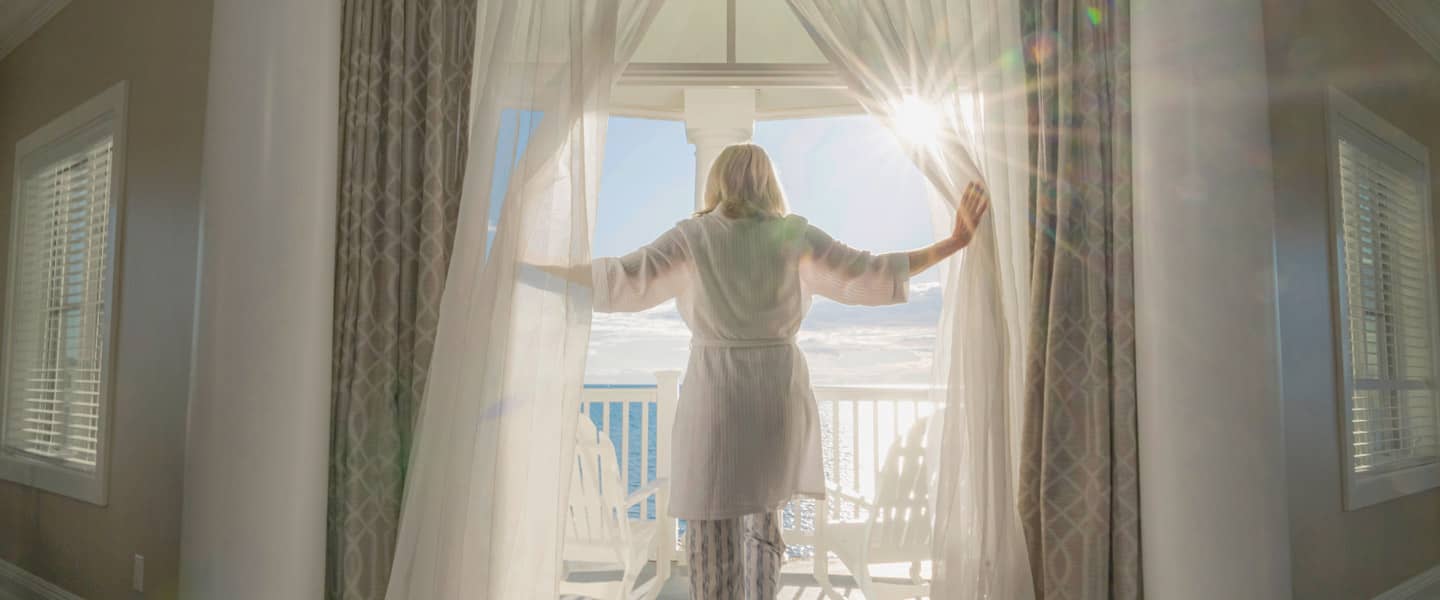 Rise & Shine, woman steps onto sunny balcony, Inn at Bay Harbor